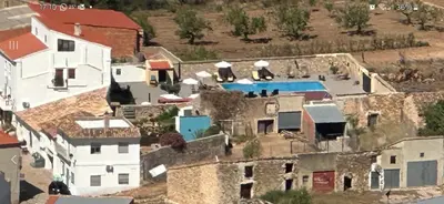 a bedroom with a bed and two white chairs at Ensueño Alojamiento Turístico in Alcublas