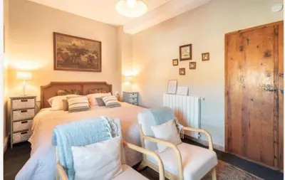a bedroom with a large bed with two chairs at Ensueño Alojamiento Turístico in Alcublas