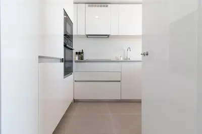 a kitchen with white cabinets and a sink at Global Vacacional, Moderno apartamento de dos terrazas con increíbles vistas al mar in Canet de Berenguer