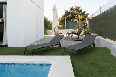 a patio with two chairs and a swimming pool at Descubre Villa Oasis - Confort, diseño y naturaleza a un paso de Valencia in Chiva