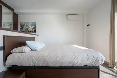 a bedroom with a bed with white sheets and a mirror at Descubre Villa Oasis - Confort, diseño y naturaleza a un paso de Valencia in Chiva