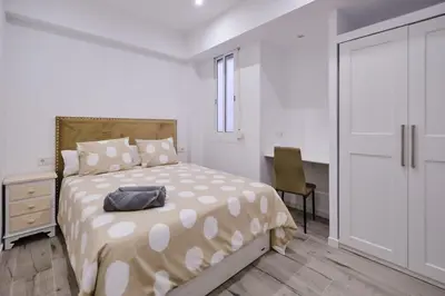 a white bedroom with a bed and a desk at Arenas flat in Valencia