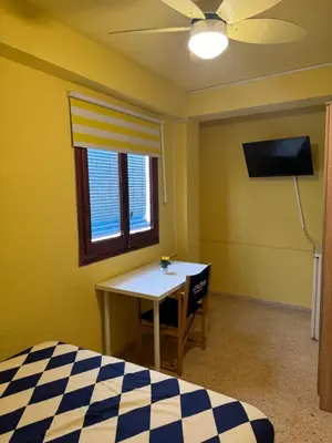 a bedroom with a bed and a table and a ceiling fan at Habitación en la playa in Valencia