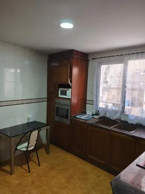 a kitchen with wooden cabinets and a table and a window at CA ÁNGEL in Anna