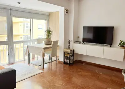 a living room with a table and a flat screen tv at ACOGEDOR PISO EN CULLERA JUNTO AL MAR in Cullera