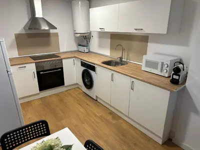 a kitchen with white cabinets and a sink and a microwave at Apartamentos Canet al Mar. in Canet de Berenguer