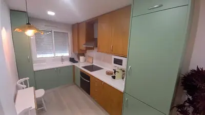 a small kitchen with wooden cabinets and a window at El rinconet in Partida de La Cañada