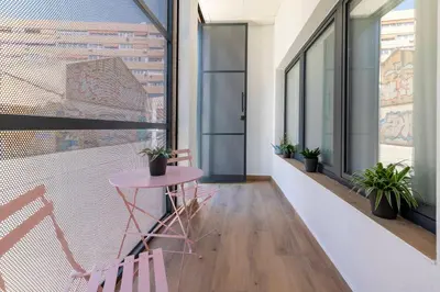 a small pink table and chairs in a room with windows at Travel Habitat Patraix Suite con Terracita in Valencia
