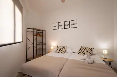 a white bedroom with two beds and two lamps at Cruz Cubierta Apartments in Valencia