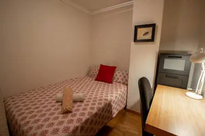 a small bedroom with a bed and a table at La casa de Lili acerca de palacio de música in Valencia