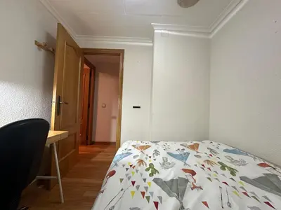 a bedroom with a bed and a desk and a door at La casa de Lili acerca de palacio de música in Valencia