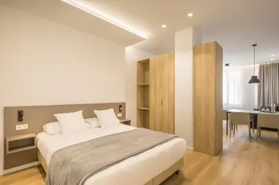 a bedroom with a large bed and a dining room at Mon Suites Jardín de Ayora in Valencia
