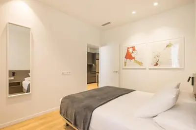 a white bedroom with a bed and a mirror at Mon Suites Jardín de Ayora in Valencia