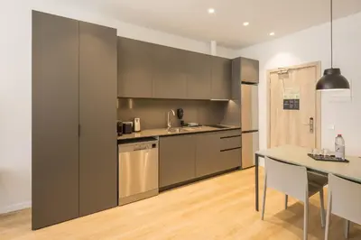 a kitchen with gray cabinets and a table with chairs at Mon Suites Jardín de Ayora in Valencia