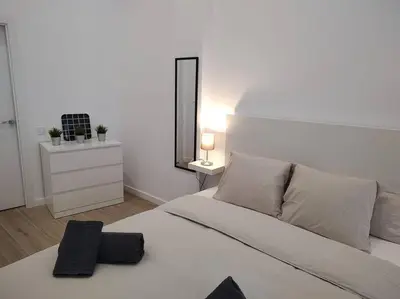 a white bedroom with a white bed and a mirror at Nuevo loft en playa y cerca del centro, AC y Wifi in Valencia