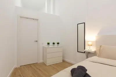 a white bedroom with a bed and a mirror at Nuevo loft en playa y cerca del centro, AC y Wifi in Valencia