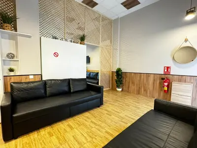 a living room with a black leather couch and wooden floors at Lliri 7 in Valencia