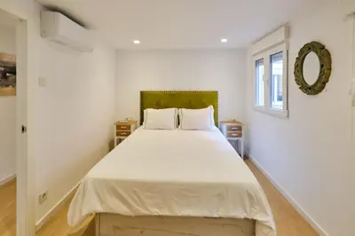 a bedroom with a large white bed with a green headboard at REINA FLAT in Valencia