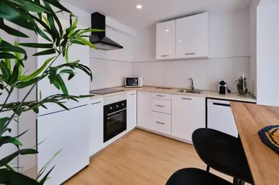 a kitchen with white cabinets and a wooden table at REINA FLAT in Valencia