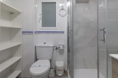 a white bathroom with a toilet and a shower at Malvarrosa Las Arenas Access in Valencia
