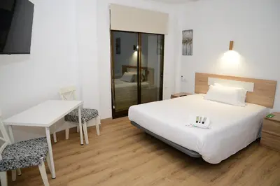 a bedroom with a bed and a table and a desk at Key Reig in Almussafes