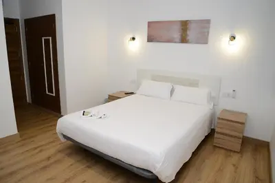 a bedroom with a large white bed and wooden floors at Key Reig in Almussafes