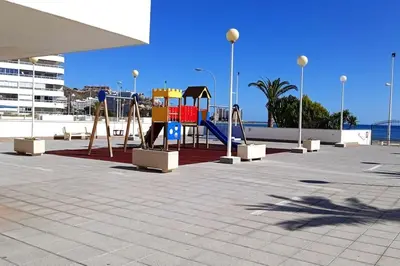 a playground in a parking lot with a swing at Apartamento frente al mar in Cullera
