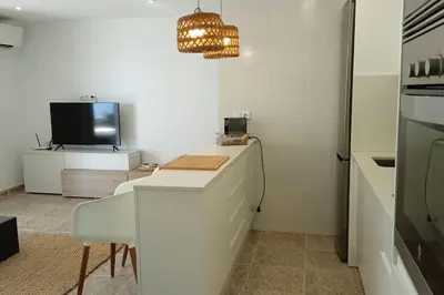 a kitchen with a desk and a television and a chandelier at Apartamento frente al mar in Cullera