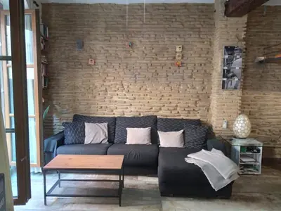 a living room with a black couch and a brick wall at Valencia Centro Suite in Valencia