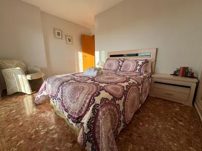 a bedroom with a large bed and a chair at Apto. Cullera vistas espectaculares primera línea in Cullera