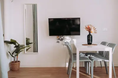 a dining room with a white table and a tv on the wall at Acogedor loft en Cabañal playa Malvarosa in Valencia