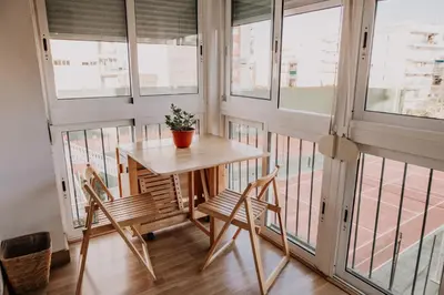 a table and chairs in a room with windows at Apartamento pobla farnals playa precioso in Las Canteras