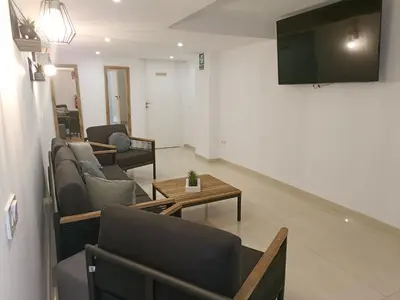 a living room with couches and a tv on a wall at MalvaLindaBeach Preciosa Casa Malvarrosa-Patacona in Valencia