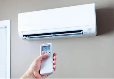 a person holding a remote control in front of a air conditioner at UIM Mediterraneo Cendoya 4 Wifi in Puerto de Sagunto