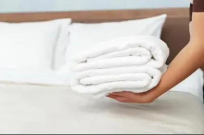 a woman is holding a stack of towels on a bed at UIM Mediterraneo Cendoya 4 Wifi in Puerto de Sagunto