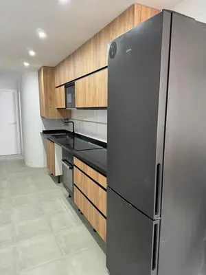 a stainless steel refrigerator in a kitchen with wooden cabinets at UIM Mediterraneo Cendoya 5 Wifi in Puerto de Sagunto