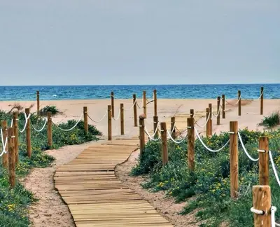 a wooden path leading to a beach with the ocean at UIM Mediterraneo Cendoya 5 Wifi in Puerto de Sagunto