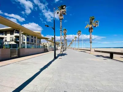 a sidewalk next to a beach with palm trees and a building at Stylish Apartment with Terrace on the BeachFrom in Valencia