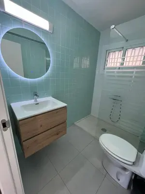 a bathroom with a sink and a toilet and a mirror at Ático El Faro Cullera in Faro de Cullera