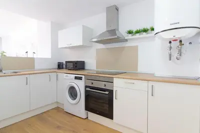a kitchen with white cabinets and a washer and dryer at Global Vacacional, Moderno apartamento con piscina y terraza en la playa de Canet in Canet de Berenguer