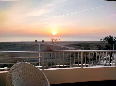 a rattan chair sitting on a balcony watching the sunset at Amanecer frente al mar in Valencia