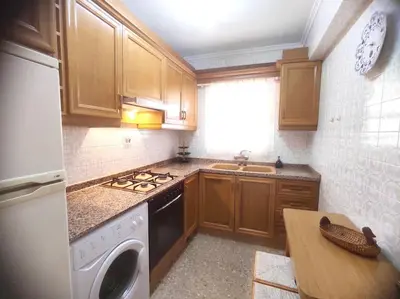 a kitchen with wooden cabinets and a stove top oven at Amanecer frente al mar in Valencia