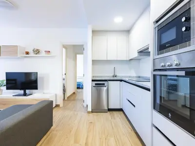 a kitchen with white cabinets and a living room at Apartment Orion-2 by Interhome in Cullera