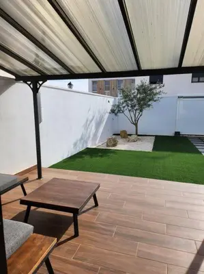 acovered patio with a table and a garden at the butterfly house in Rafelbuñol