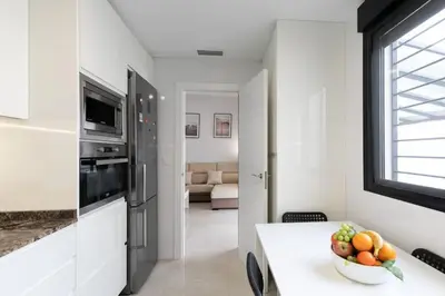 a white kitchen with a bowl of fruit on a table at the butterfly house in Rafelbuñol