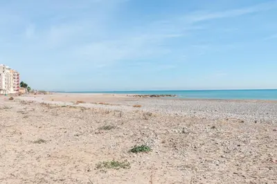 a sandy beach with a building and the ocean at Burriana Beach Retreat: Pool & Comfort in Burriana
