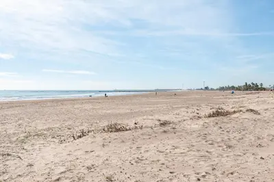 a sandy beach with people in the water at Burriana Beach Retreat: Pool & Comfort in Burriana