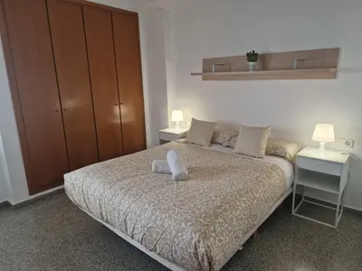 a bedroom with a bed with two tables and a cabinet at Playa Patacona con vistas al mar in Valencia