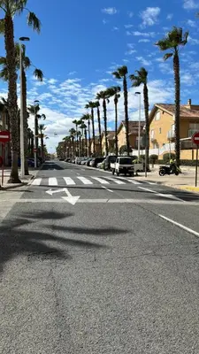 an empty street with palm trees on the side of the road at Playa Patacona con vistas al mar in Valencia