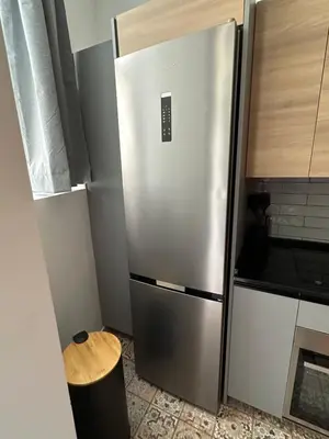 a stainless steel refrigerator in a kitchen with a stool at Beach Apartments Valencia 2 in Valencia